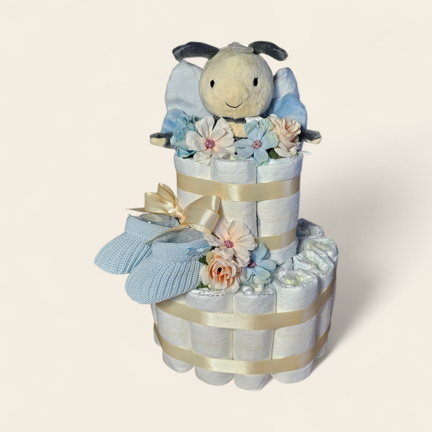 Luiertaart 2 laags met zacht gele accenten en Happy Horse bijtje rammelaar